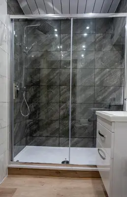 a shower with a glass door in a bathroom at Curtis Apartment in Glasgow