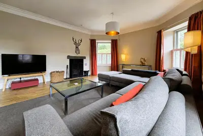a living room with a couch and a tv at Balmory Stables North, luxury stable conversion in Ascog