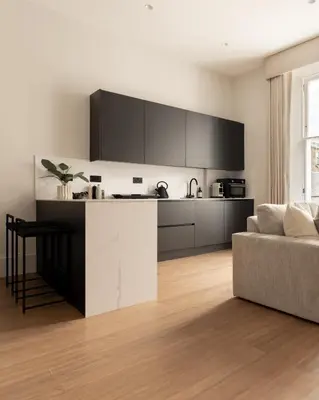 a kitchen with black and white cabinets and a couch at Moment Blythswood St in Glasgow