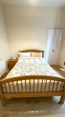 a bedroom with a wooden bed with a floral bedspread at Glasgow One Bedroom Flat close to city centre and all amenities in Glasgow