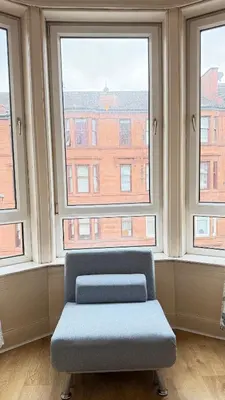 a chair sitting in a room with two windows at Glasgow One Bedroom Flat close to city centre and all amenities in Glasgow