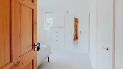 a white bedroom with a bed and a mirror at Stag's View Lodge in Edinburgh
