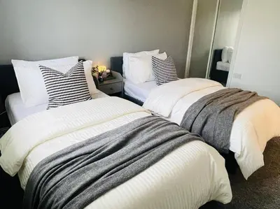two beds in a room with white and gray sheets at Elegant 3BR house in Glasgow in Garthamlock