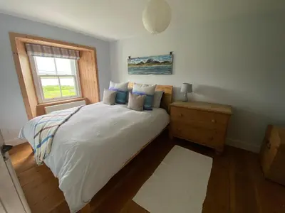 a bedroom with a large bed with a window at Smithy House in Crinan