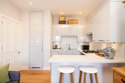 a kitchen with white cabinets and bar stools at Edinburgh Stockbridge Charm Apartment in Edinburgh