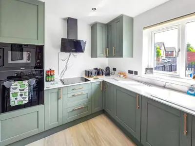 a kitchen with green cabinets and a window at Bright & Modern 3-Bed House Next To Glasgow Airport in Abbotsinch