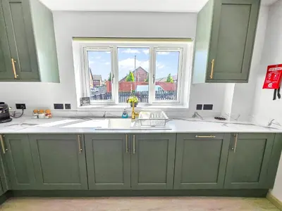 a kitchen with green cabinets and a window at Bright & Modern 3-Bed House Next To Glasgow Airport in Abbotsinch