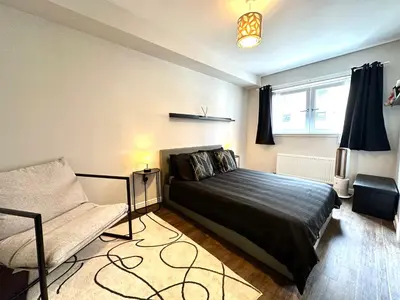 a bedroom with a bed and a chair in it at The Clyde Retreat, 2 Bedrooms in Glasgow