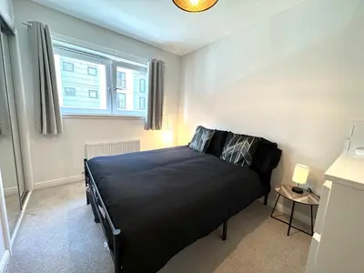 a bedroom with a black bed in a room at The Clyde Retreat, 2 Bedrooms in Glasgow