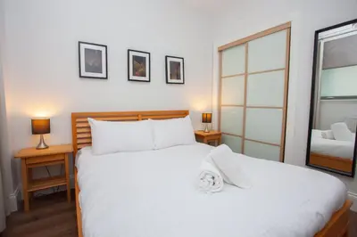 a bedroom with a large white bed and a mirror at Stylish 3rd Floor Flat in Historic Merchant City in Glasgow