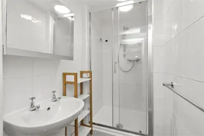 a white bathroom with a sink and a shower at Haymarket Edinburgh Flat Sleeps 4 in Edinburgh