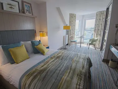 a bedroom with a large bed and a dining room at The Waterside Hotel & Spa in Seamill
