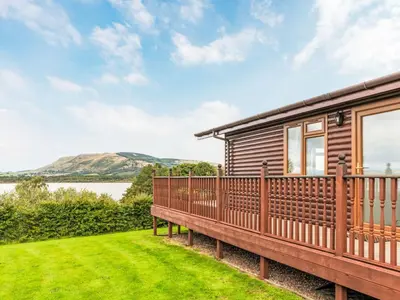a log cabin with a deck and a view of the water at Chalet Loch Side Lodge 5 by Interhome in Kinross