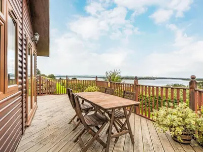 a wooden deck with a wooden table and chairs at Chalet Loch Side Lodge 5 by Interhome in Kinross