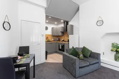a living room with a couch and a table and a kitchen at Sleek Canalside Stay in Edinburgh in Edinburgh