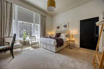 a bedroom with a bed and a chair and a window at The Burnbank Experience in Glasgow