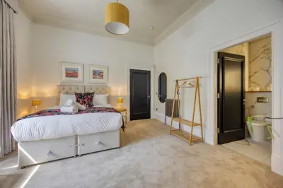 a bedroom with a large bed and a bathroom at The Burnbank Experience in Glasgow