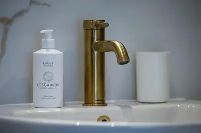 a bathroom sink with a gold faucet and a bottle of soap at The Burnbank Experience in Glasgow