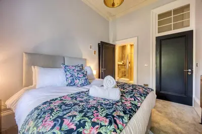 a bedroom with a large bed with a floral bedspread at The Burnbank Experience in Glasgow