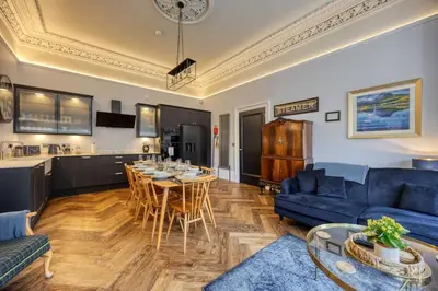 a living room with a blue couch and a table at The Burnbank Experience in Glasgow