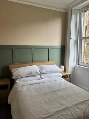 a bedroom with a bed with white sheets and a window at Modern One Bed Flat, Historic Old Town Edinburgh in Edinburgh