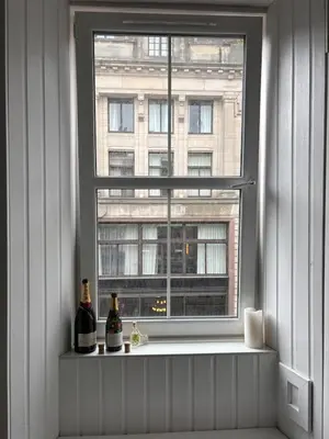 a window with two bottles of wine on a ledge at Modern One Bed Flat, Historic Old Town Edinburgh in Edinburgh