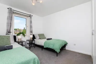 a bedroom with two beds and a window at 2 Bedroom Flat - Free Parking- by Holiday Homes in Clydebank