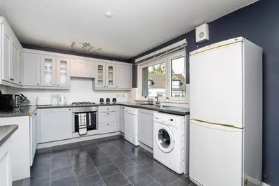 a kitchen with white cabinets and a washer and dryer at 2 Bedroom Flat - Free Parking- by Holiday Homes in Clydebank