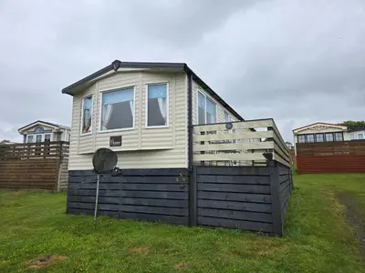 a tiny house sitting on top of a yard at Lovely Caravan number 96 at Three Lochs Holiday Park in Kirkcowan