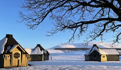 a row of houses in the snow with a lake at Carnethy Cabin in Kirknewton