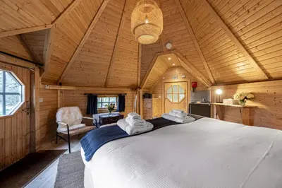 a bedroom with a large bed in a wooden room at Carnethy Cabin in Kirknewton