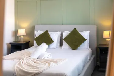 a bedroom with a white bed with two pillows at No15 Ellis House - Donnini Apartments in Kilmarnock