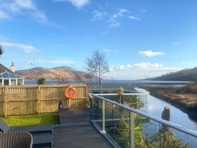a house with a deck with a view of a river at Riverside Cottage in Lamlash