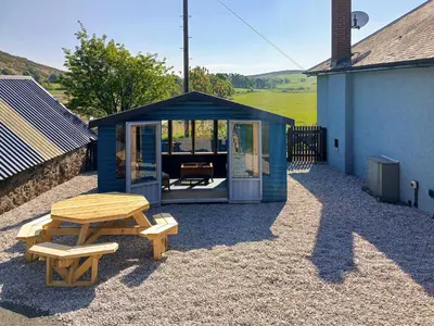 a blue shed with a picnic table and benches at Bendhu in Mill of Fortune