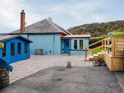 a dog sitting in front of a blue house at Bendhu in Mill of Fortune