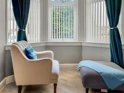 a bedroom with a chair and a bed and windows at Homely Base in Crossgates