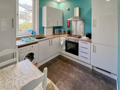 a kitchen with white cabinets and a dishwasher at Homely Base in Crossgates
