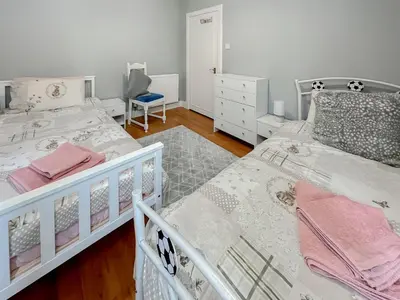 a bedroom with two beds and a chair at Homely Base in Crossgates