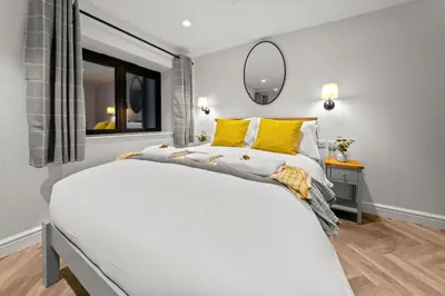 a bedroom with a large white bed with yellow pillows at The Salt Room Modern 1 Bedroom Home By AltoLuxo Short Lets Serviced Accommodation With Free Wifi & Parking in Moffat