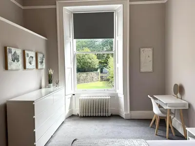 a bedroom with a window and a white dresser and a desk at New Town luxury 1 bed apartment in Edinburgh