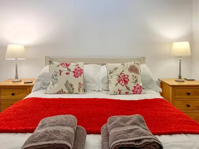 a bedroom with a red bed with two lamps at Riverview Cottage in Kenmore