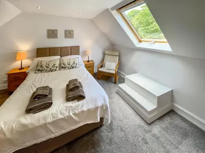 a bedroom with a bed with a window and a chair at Riverview Cottage in Kenmore