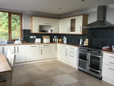 a kitchen with white cabinets and a stove top oven at Memorising sea views contemporary, spacious 4 bedroom coastal villa near Oban in Craobh Haven