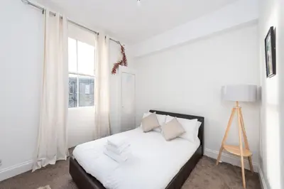 a white bedroom with a bed and a window at Cosy 2-bedroom Edinburgh flat close to city centre in Edinburgh