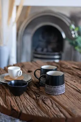 a table with cups and saucers on it with a fireplace at Cosy 2-bedroom Edinburgh flat close to city centre in Edinburgh