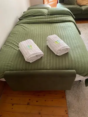 a green bed with two white pillows on it at Charming flat in beautiful area in Edinburgh