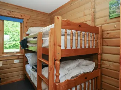 a bedroom with two bunk beds in a log cabin at Shore Lodge Brodick Castle in Brodick