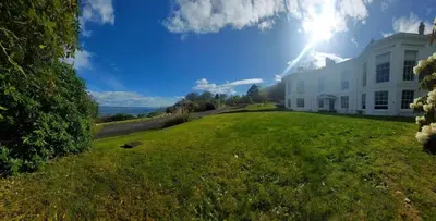 a large white house with the sun in the sky at 2 Bed Flat - Sleeps 4 - Pets - Parking - Wifi in Rothesay
