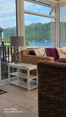 a living room with a couch and a table at Jenny's Bay with Hot Tub in Lochgoilhead