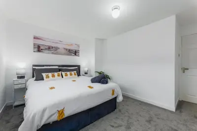 a bedroom with a large bed with white sheets at Comfortable & cozy Home Stay in East Kilbride
